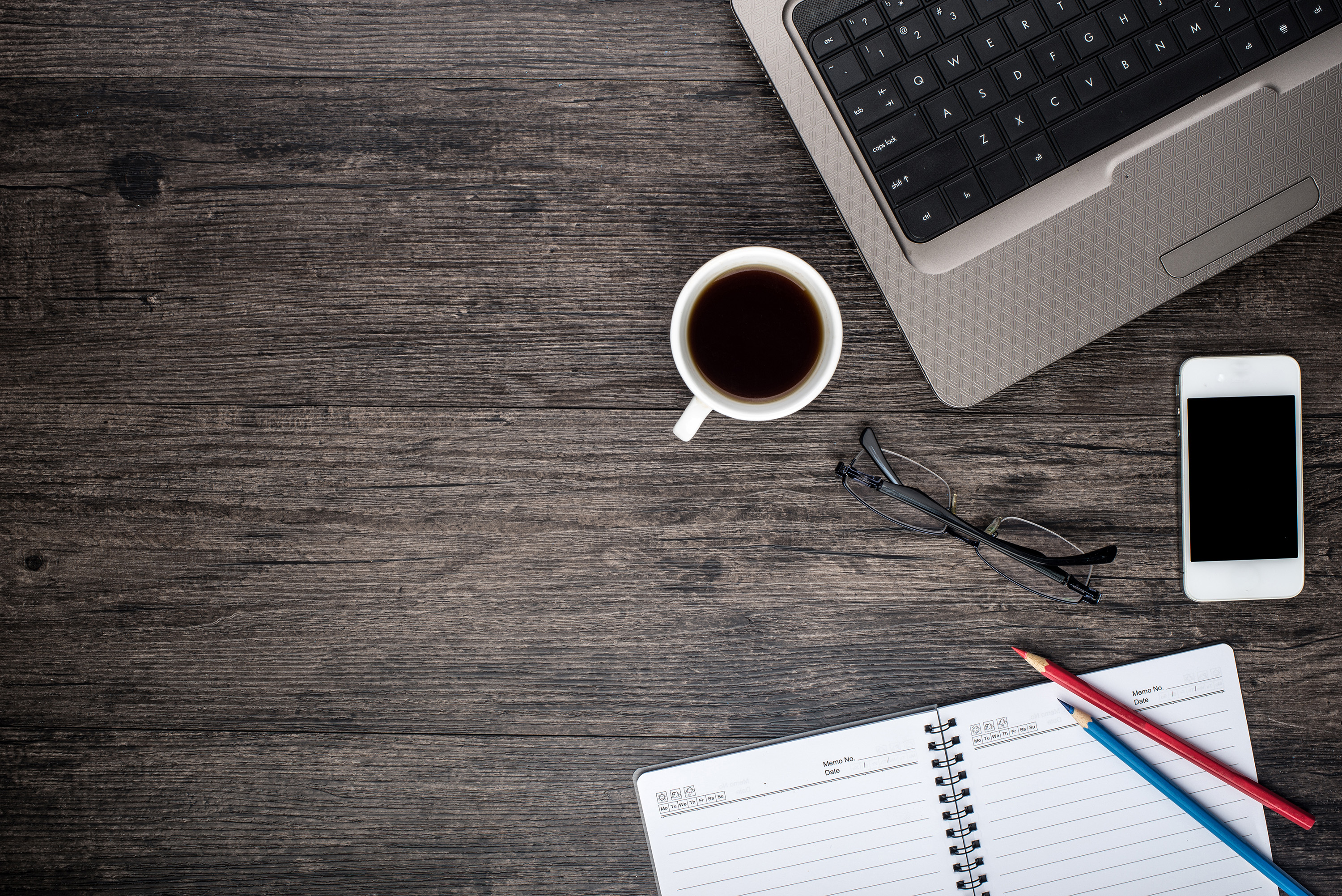 Office desk with laptop computer, planner, mobile smartphone and coffee cup.